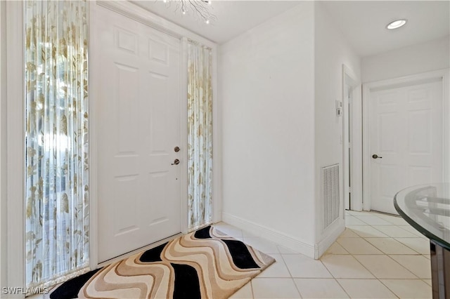 foyer with a notable chandelier, light tile patterned floors, baseboards, and visible vents