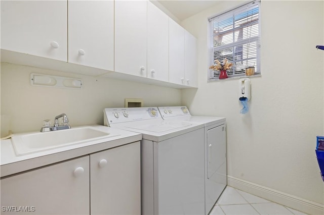 washroom with cabinet space, independent washer and dryer, baseboards, and a sink