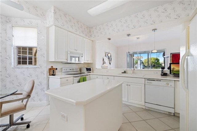 kitchen featuring a sink, white appliances, light tile patterned floors, and wallpapered walls