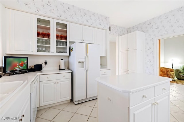 kitchen featuring white cabinets, wallpapered walls, glass insert cabinets, and white fridge with ice dispenser