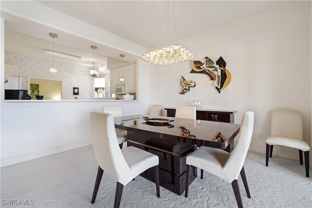 carpeted dining room featuring a notable chandelier and baseboards