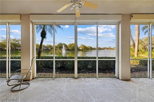 unfurnished sunroom with ceiling fan and a water view