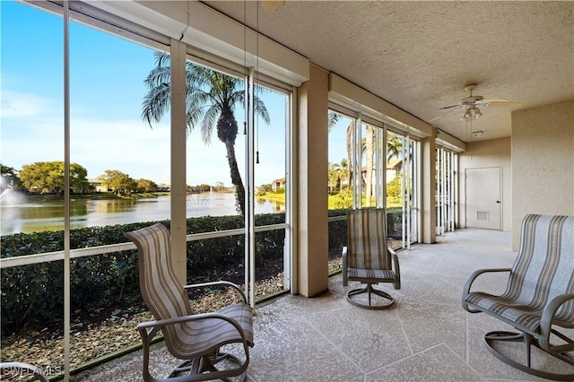 sunroom / solarium with plenty of natural light, a ceiling fan, and a water view