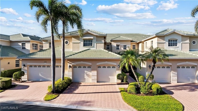 view of front of property with a tile roof, decorative driveway, a garage, and stucco siding