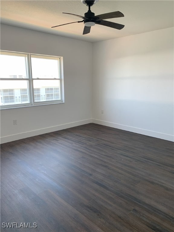 empty room featuring dark wood finished floors, baseboards, and ceiling fan