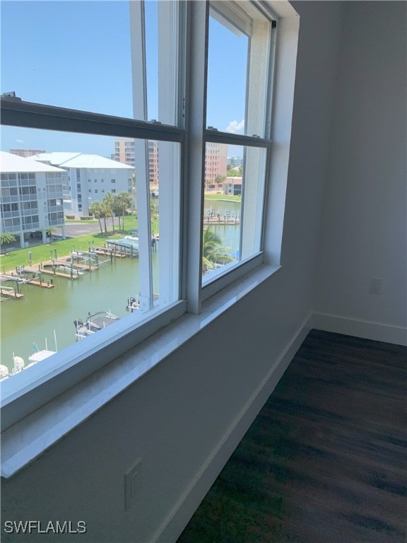 interior space with baseboards, a water view, and dark wood-style floors