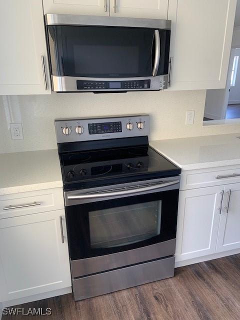 kitchen featuring light countertops, white cabinets, dark wood-style floors, and stainless steel appliances