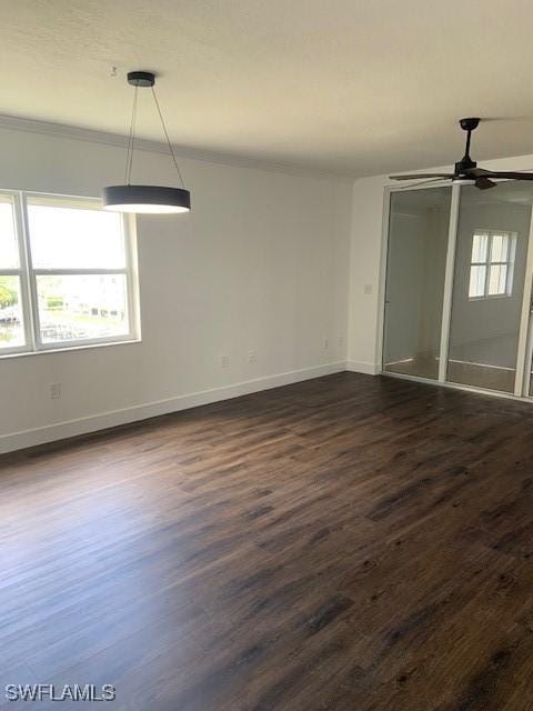 spare room with baseboards, a ceiling fan, dark wood-style floors, and crown molding