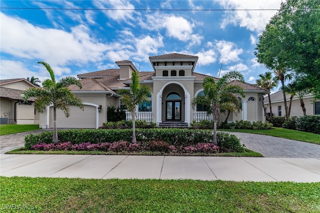 mediterranean / spanish-style house with driveway, a tile roof, a garage, and stucco siding