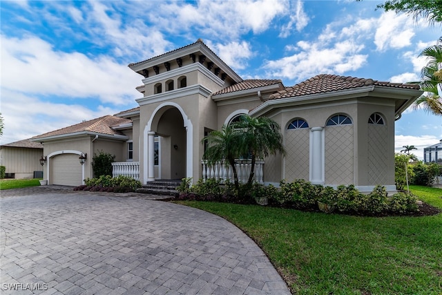 mediterranean / spanish home featuring a garage, a tiled roof, decorative driveway, and stucco siding