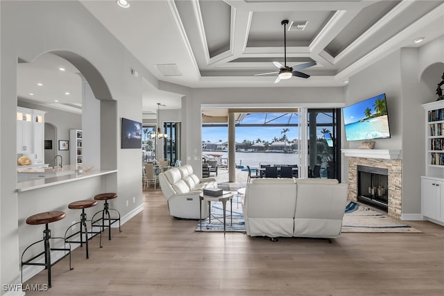 living room with ceiling fan with notable chandelier, a fireplace, coffered ceiling, visible vents, and light wood-style floors