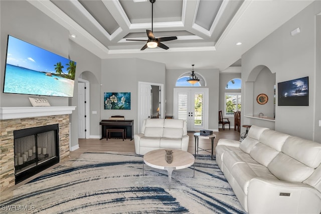 living area with a towering ceiling, a fireplace, ornamental molding, and wood finished floors