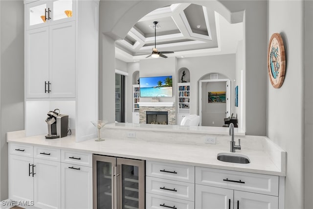 bar featuring ceiling fan, beverage cooler, a fireplace, coffered ceiling, and a sink