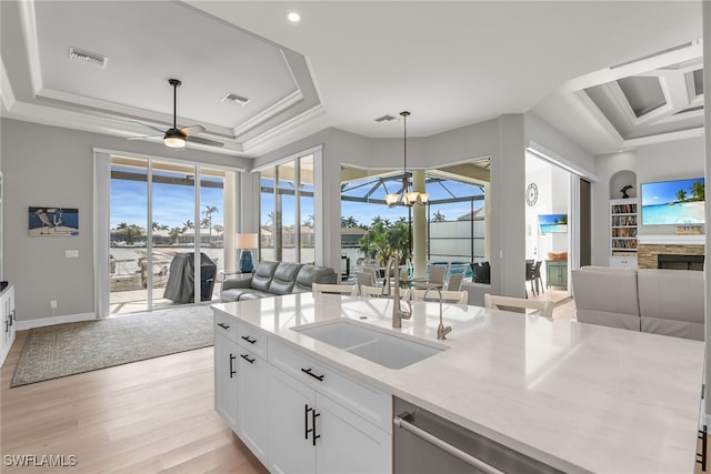 kitchen featuring a tray ceiling, open floor plan, visible vents, and a sink