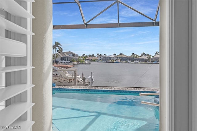 outdoor pool with a residential view, glass enclosure, and a water view