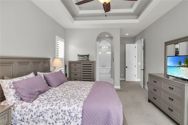 bedroom featuring arched walkways, ensuite bathroom, light carpet, baseboards, and a raised ceiling