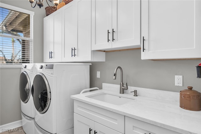 laundry room with washing machine and dryer, a sink, cabinet space, and baseboards