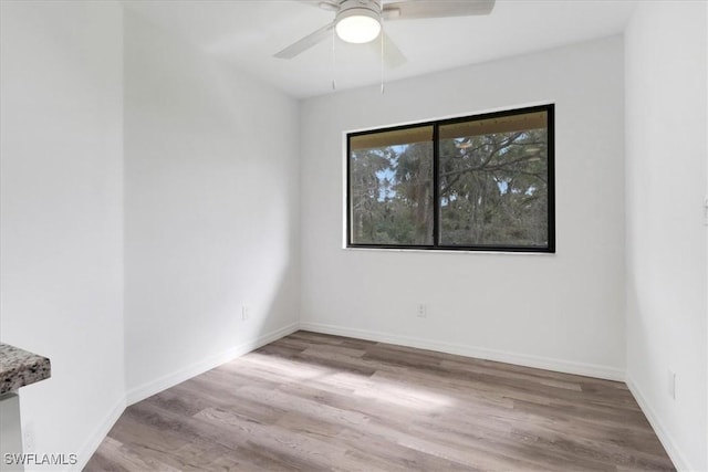 empty room featuring light wood-type flooring, baseboards, and a ceiling fan