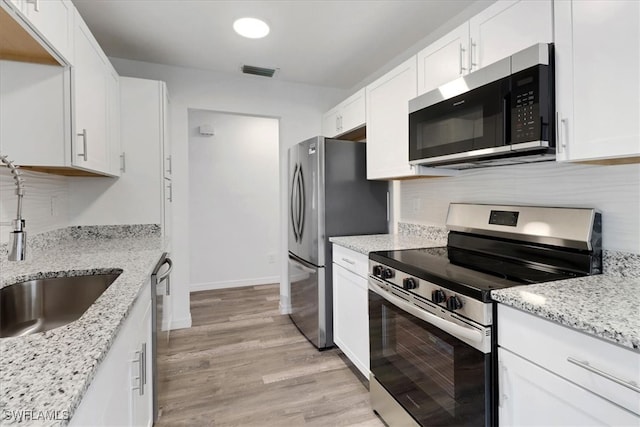 kitchen featuring tasteful backsplash, visible vents, white cabinets, appliances with stainless steel finishes, and light stone countertops