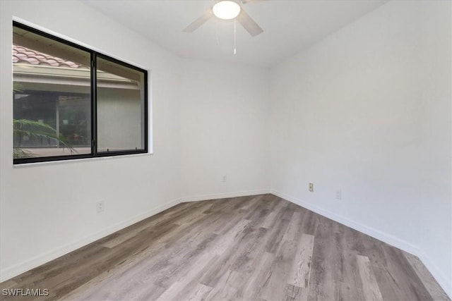 spare room featuring light wood finished floors, ceiling fan, and baseboards