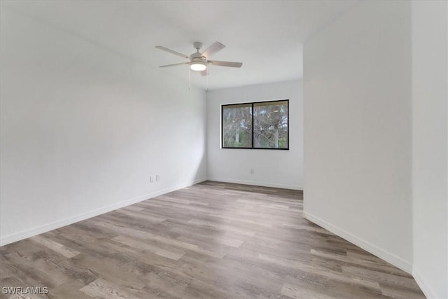 spare room with ceiling fan, light wood finished floors, and baseboards