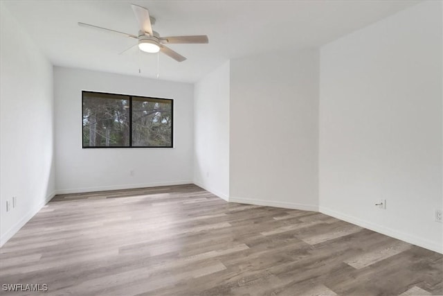 spare room with ceiling fan, light wood-style flooring, and baseboards