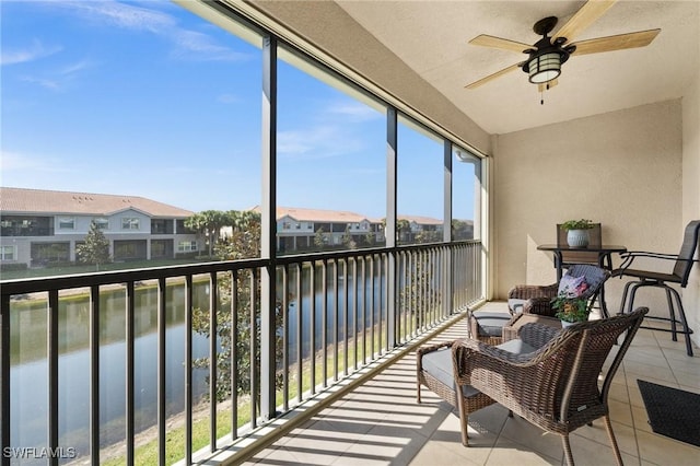 sunroom featuring a water view, a residential view, and a ceiling fan