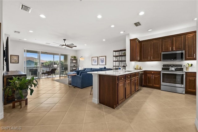 kitchen with visible vents, open floor plan, a peninsula, stainless steel appliances, and light countertops