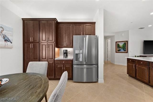 kitchen with light countertops, stainless steel fridge, dark brown cabinets, and light tile patterned floors