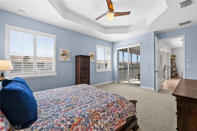 bedroom with light carpet, a raised ceiling, visible vents, and baseboards