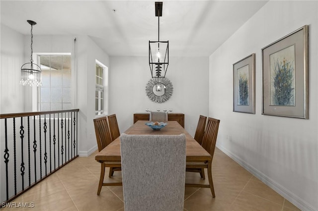 dining space with a chandelier, light tile patterned flooring, and baseboards