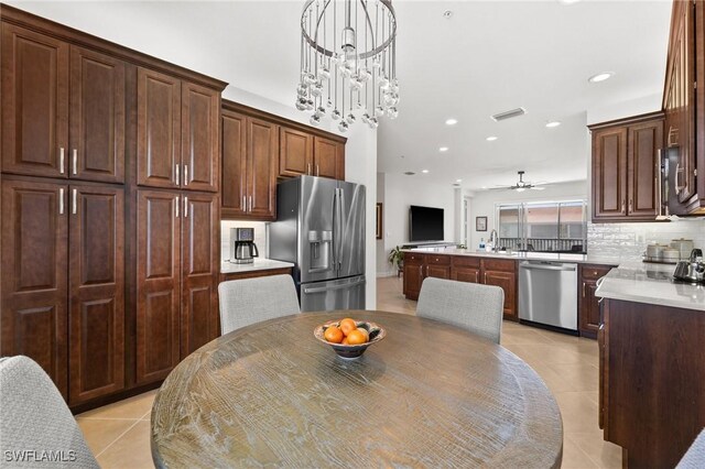 kitchen featuring decorative light fixtures, light countertops, backsplash, an inviting chandelier, and appliances with stainless steel finishes