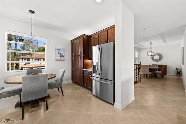 kitchen featuring an inviting chandelier, stainless steel fridge, light tile patterned floors, and pendant lighting