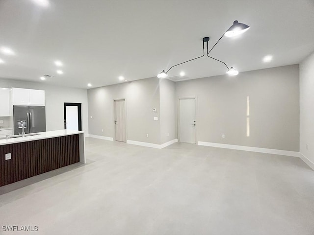 kitchen with concrete flooring, light countertops, white cabinetry, and stainless steel fridge with ice dispenser