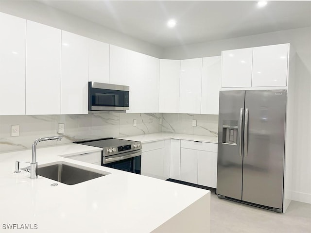 kitchen featuring modern cabinets, appliances with stainless steel finishes, white cabinets, and a sink