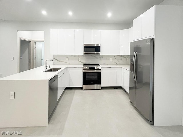 kitchen with light countertops, appliances with stainless steel finishes, a sink, and white cabinets