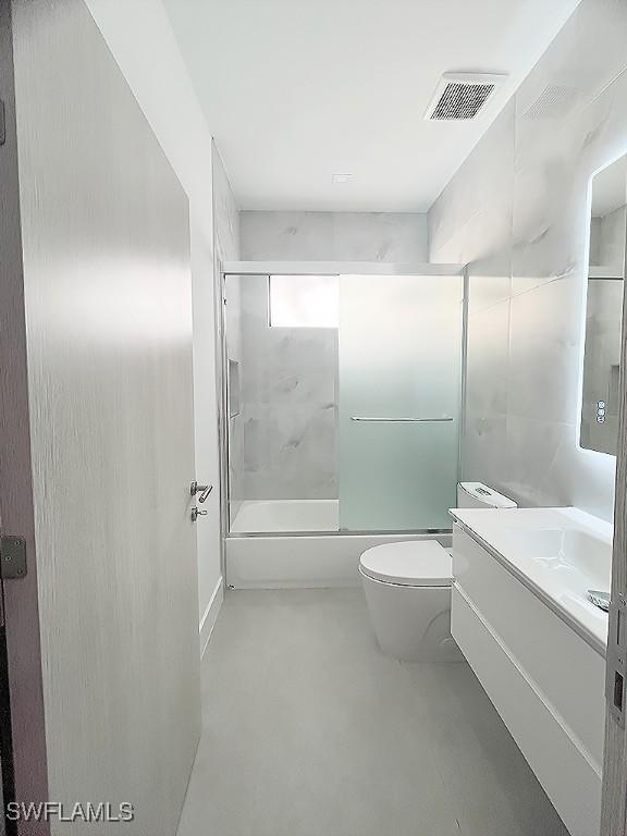 full bathroom featuring toilet, bath / shower combo with glass door, vanity, and visible vents