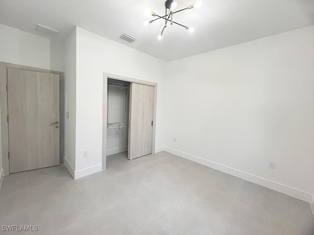 unfurnished bedroom featuring baseboards, visible vents, a chandelier, and a closet