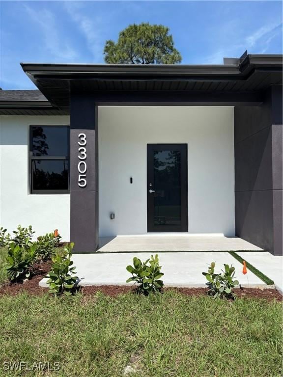 property entrance with a yard and stucco siding