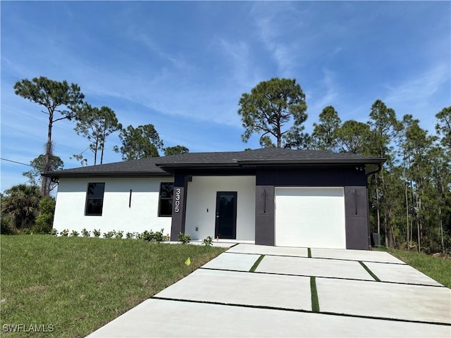 view of front of property featuring a garage, driveway, a front yard, and stucco siding