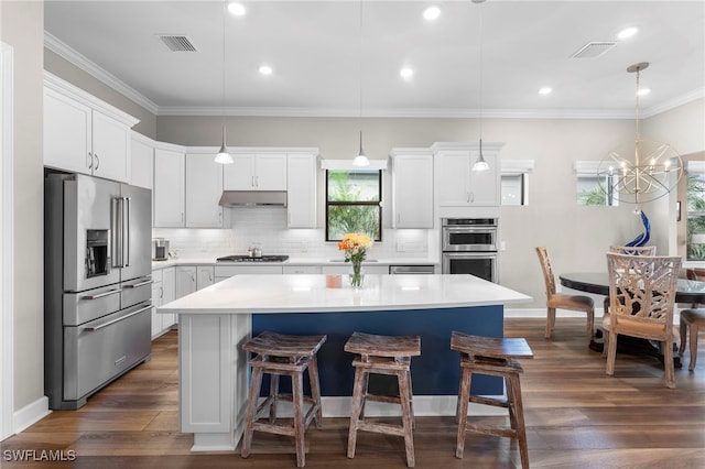 kitchen featuring a center island, stainless steel appliances, visible vents, ornamental molding, and under cabinet range hood