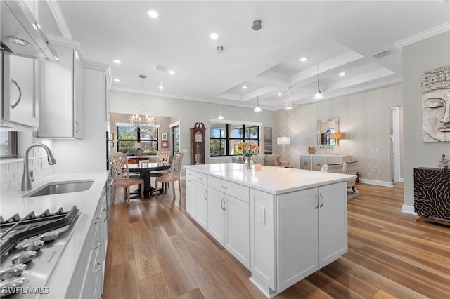 kitchen with crown molding, stainless steel gas cooktop, a sink, and wood finished floors