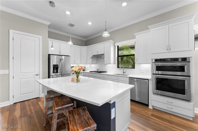 kitchen with under cabinet range hood, a sink, visible vents, appliances with stainless steel finishes, and tasteful backsplash