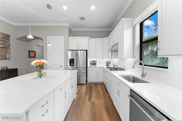 kitchen featuring under cabinet range hood, crown molding, appliances with stainless steel finishes, and a sink