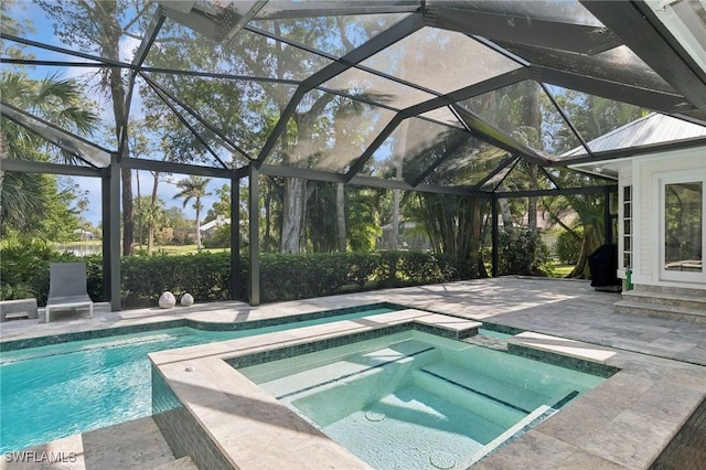 view of pool with a pool with connected hot tub, glass enclosure, and a patio