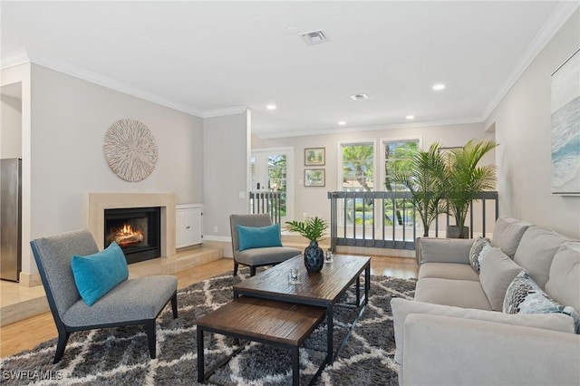 living room with recessed lighting, wood finished floors, visible vents, a lit fireplace, and ornamental molding