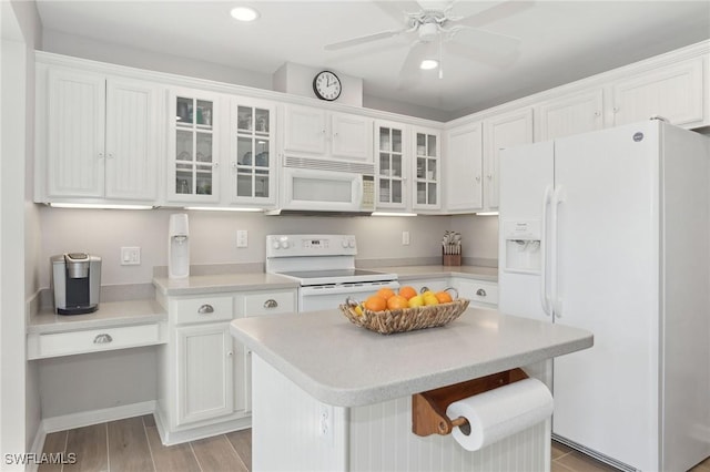 kitchen featuring a center island, light countertops, glass insert cabinets, white cabinets, and white appliances