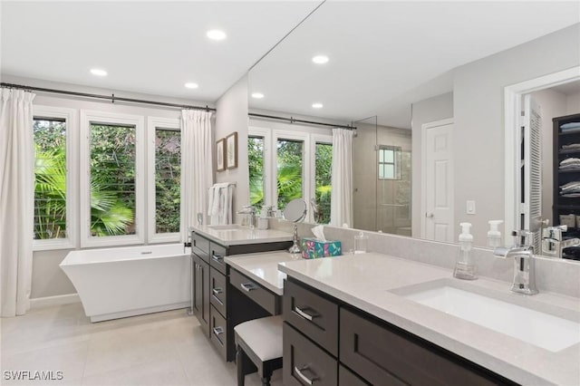 bathroom featuring recessed lighting, a soaking tub, tile patterned flooring, and vanity