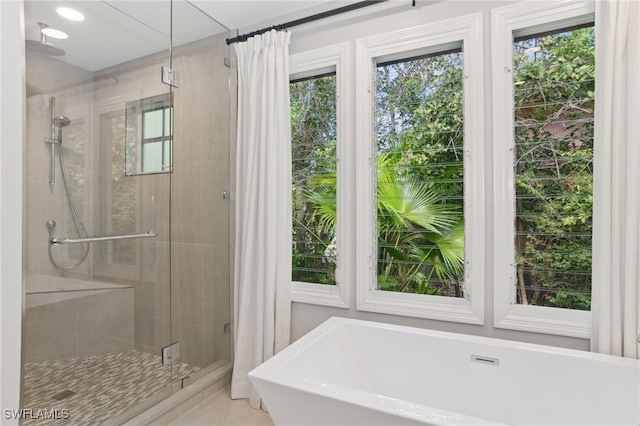 bathroom featuring a shower stall and a freestanding bath