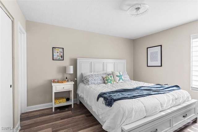 bedroom featuring multiple windows, baseboards, and dark wood finished floors